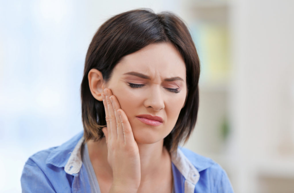 Woman rubbing her jaw because she has TMD.