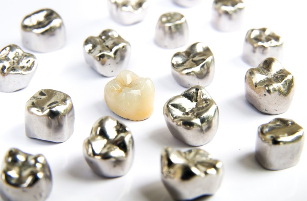 Dental crowns made from different materials resting on flat white surface
