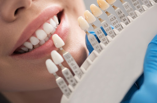 Smiling dental patient next to row of ceramic crowns