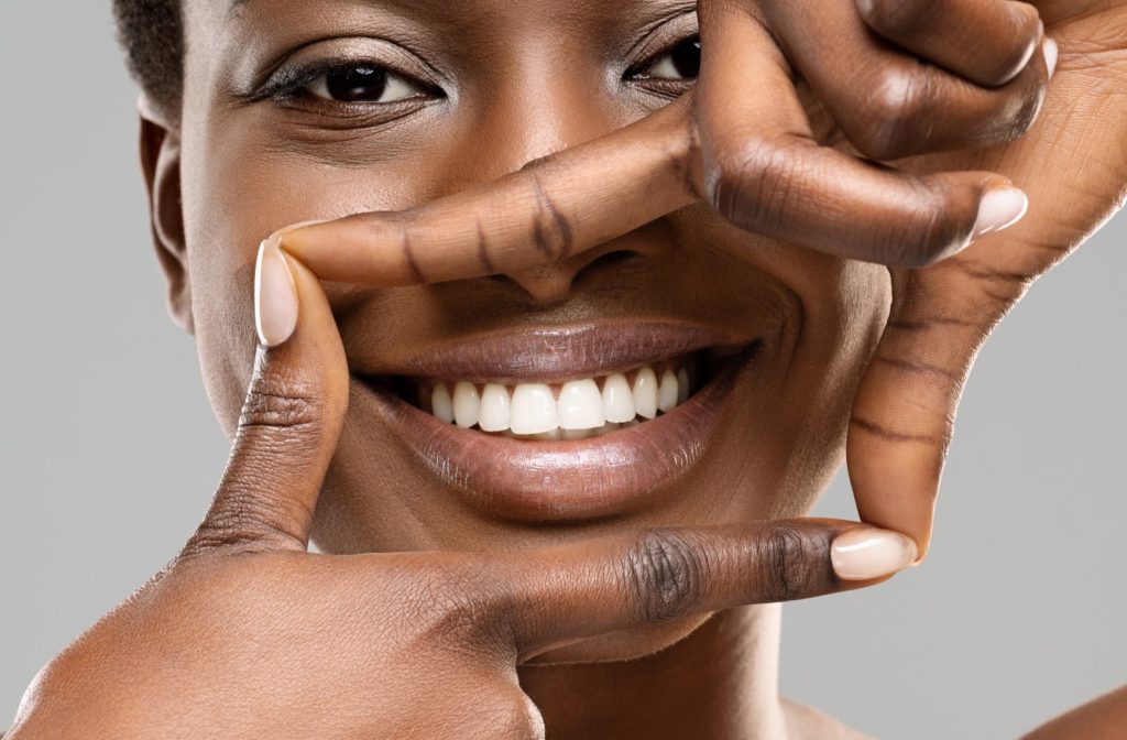 Woman smiling and framing her perfect white teeth with her fingers
