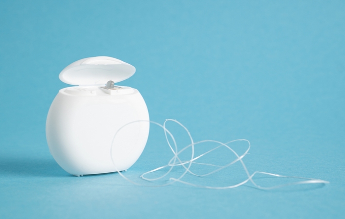 Dental floss in front of a light blue background