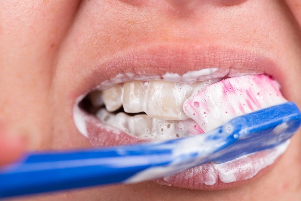 A close up of someone's mouth while they brush their teeth with a manual toothbrush