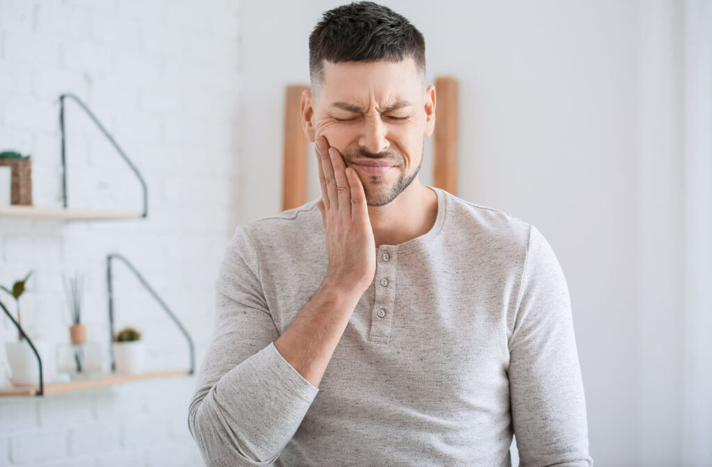 A young man holding the right side of his face in pain due to a tooth infection.