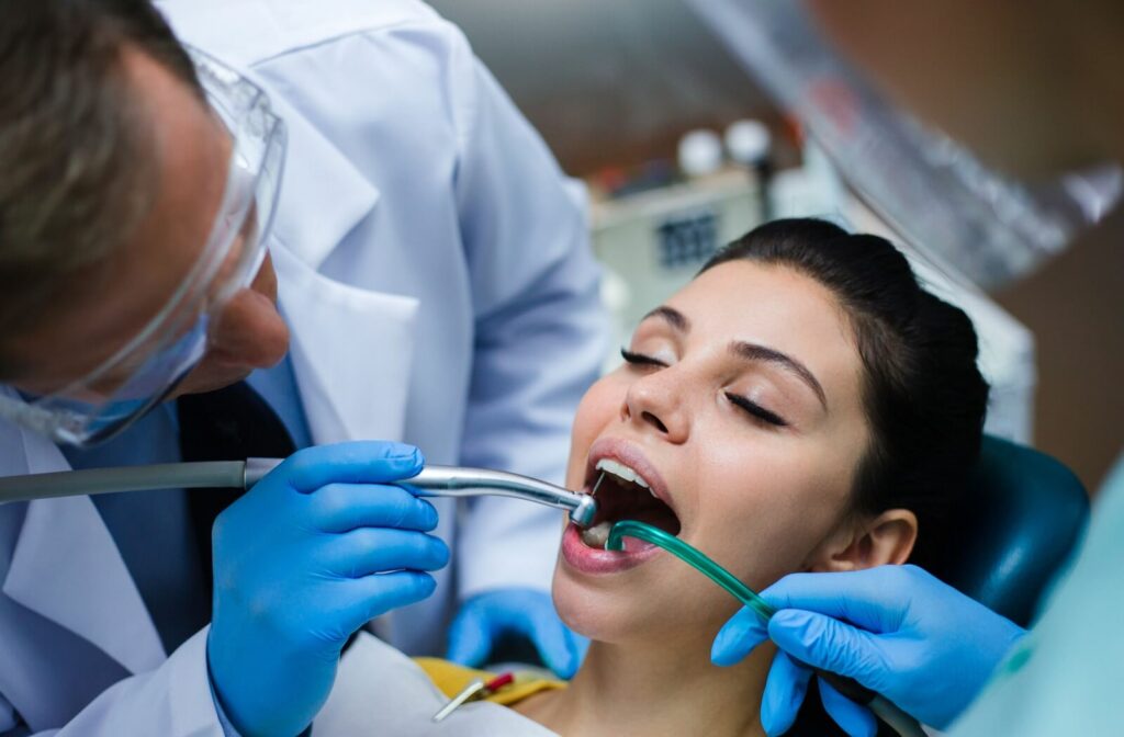 A male dentist examining a female patient's teeth to look for signs of infection.