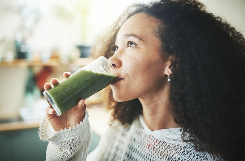 A person drinking a nutritious and easy-to-eat green smoothie.
