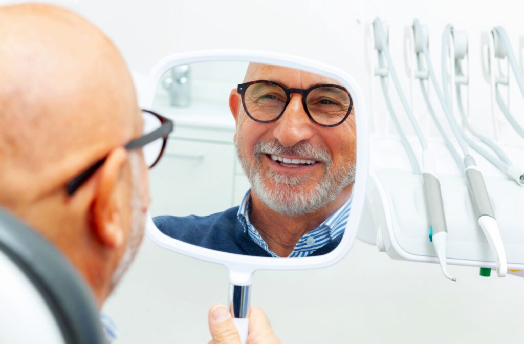 Someone smiles at themselves in a mirror after getting their dental implants done.