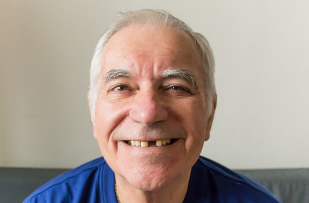 A senior person smiling with a gap in their teeth where a tooth is missing