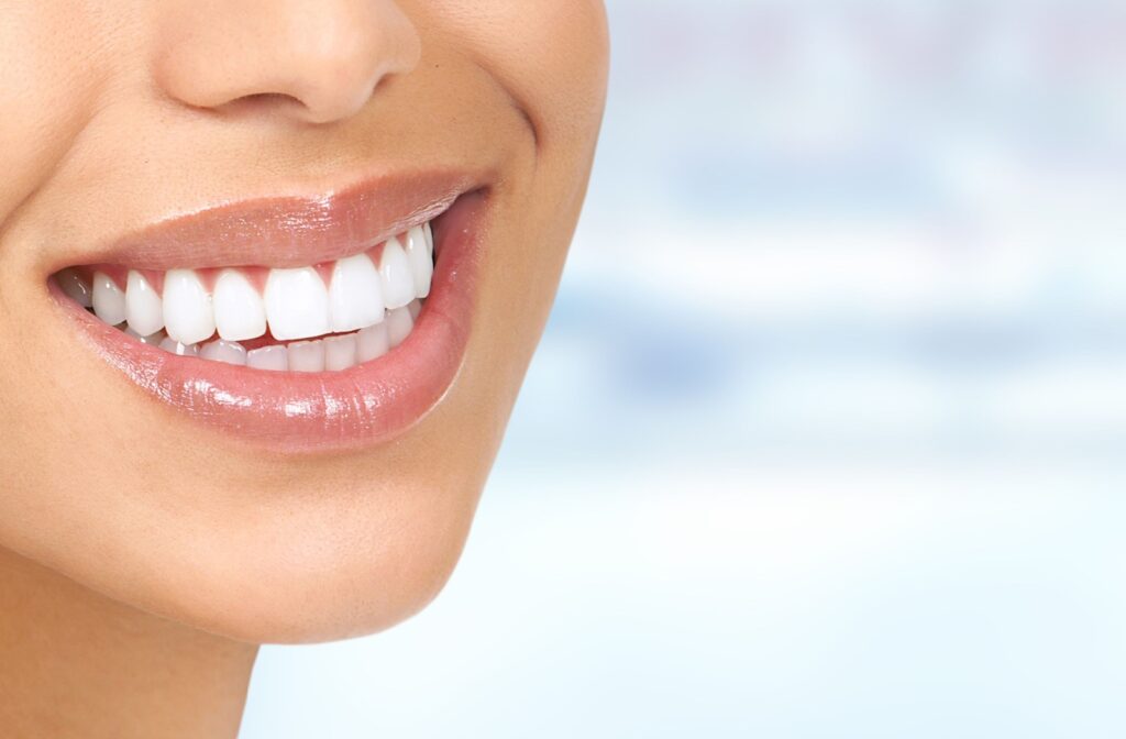 A person smiling with perfect teeth after receiving a dental implant