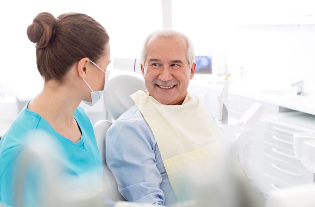 A senior person smiling at the dentist during a discussion about dental implants