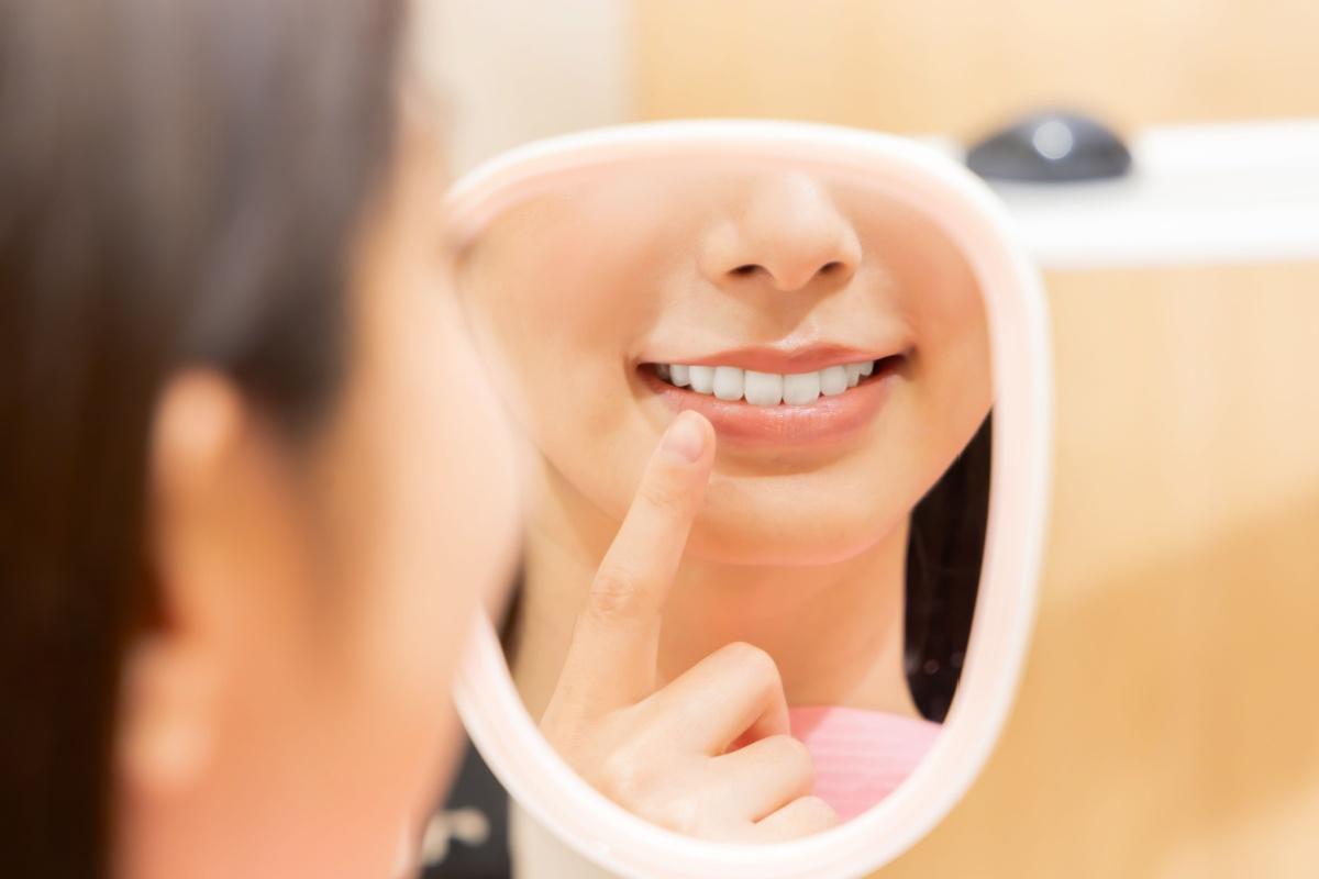 A person looking at their teeth in a mirror while at the dentist